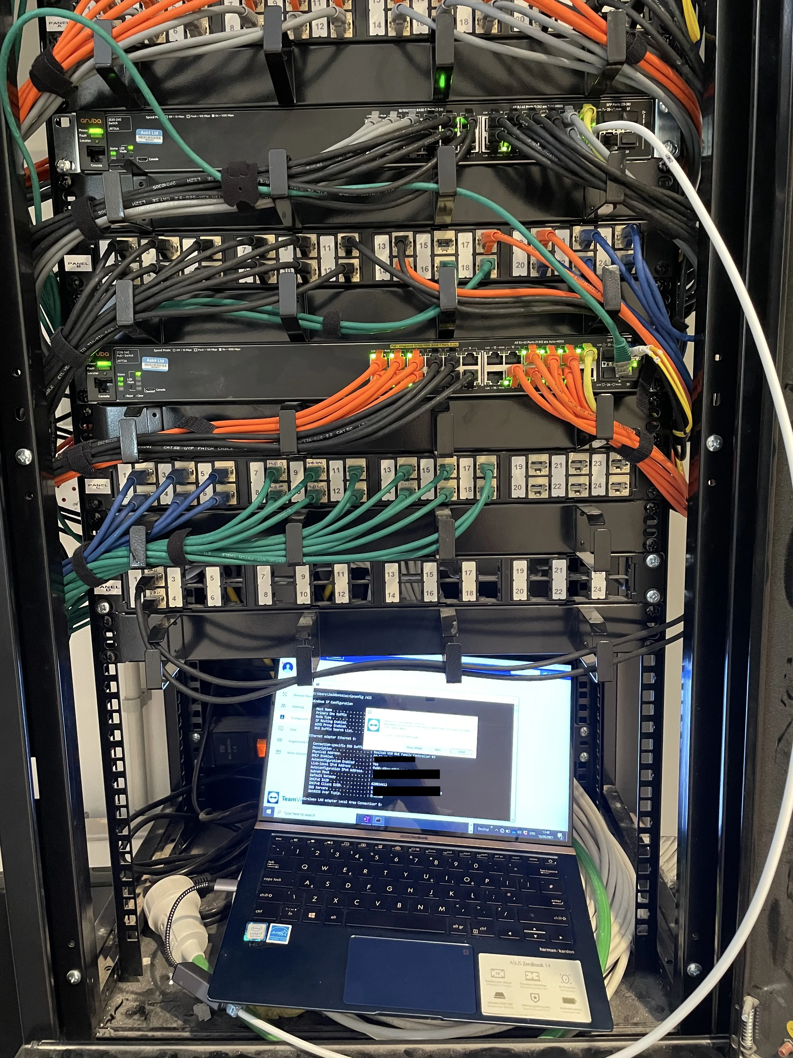 Network equipment rack with neatly routed cables and a laptop showing configuration tools