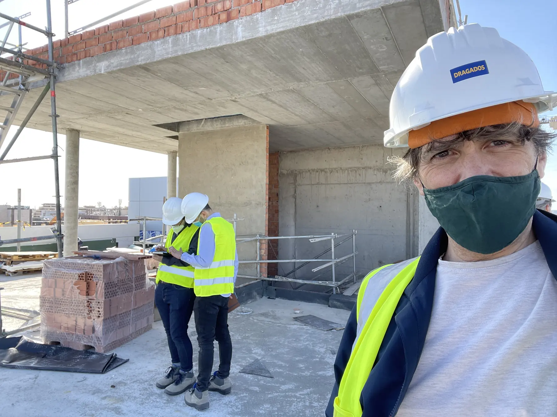 Project lead and two workers in high-visibility clothing and hard hats on an unfinished building floor