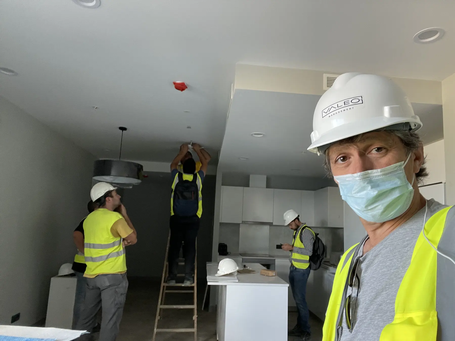 Workers in high-visibility clothing carrying out installation work inside a residence room